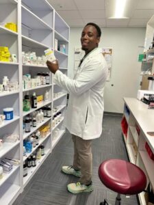 African American man in a white coat holding medication in the pharmacy.